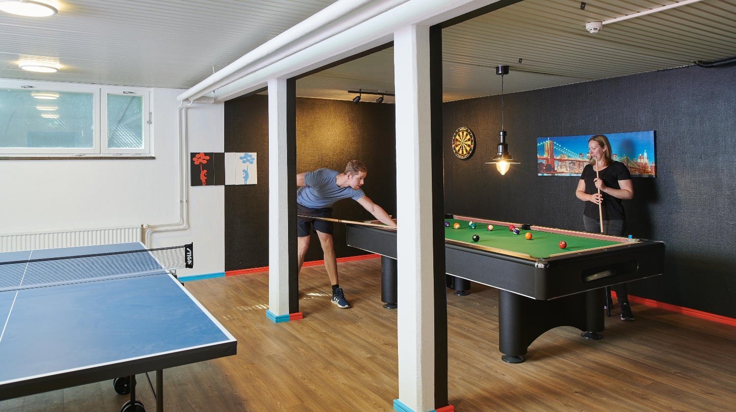 Game room with a ping pong table and two students playing pool