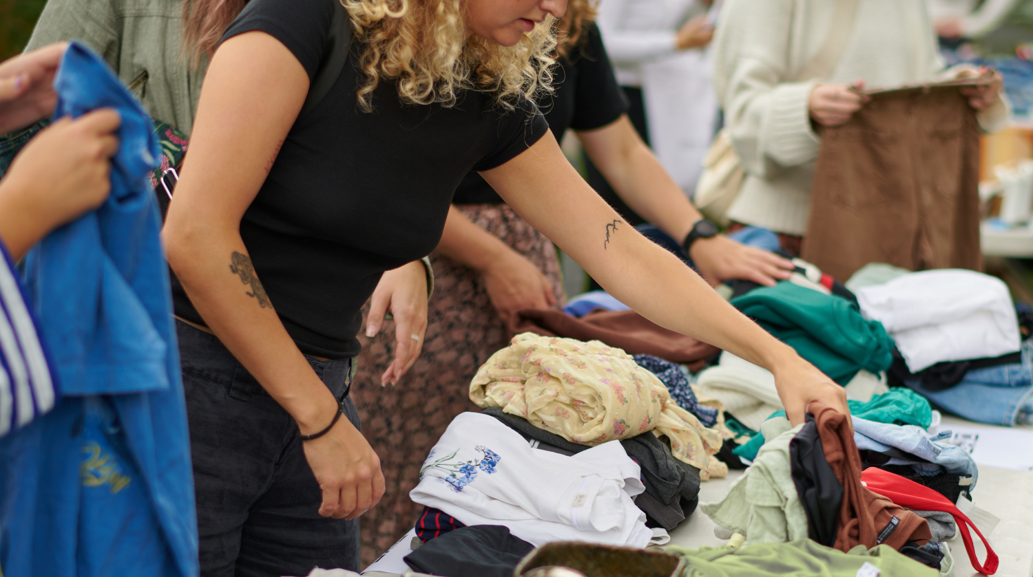 A girl touching clothes on a table at a flea market