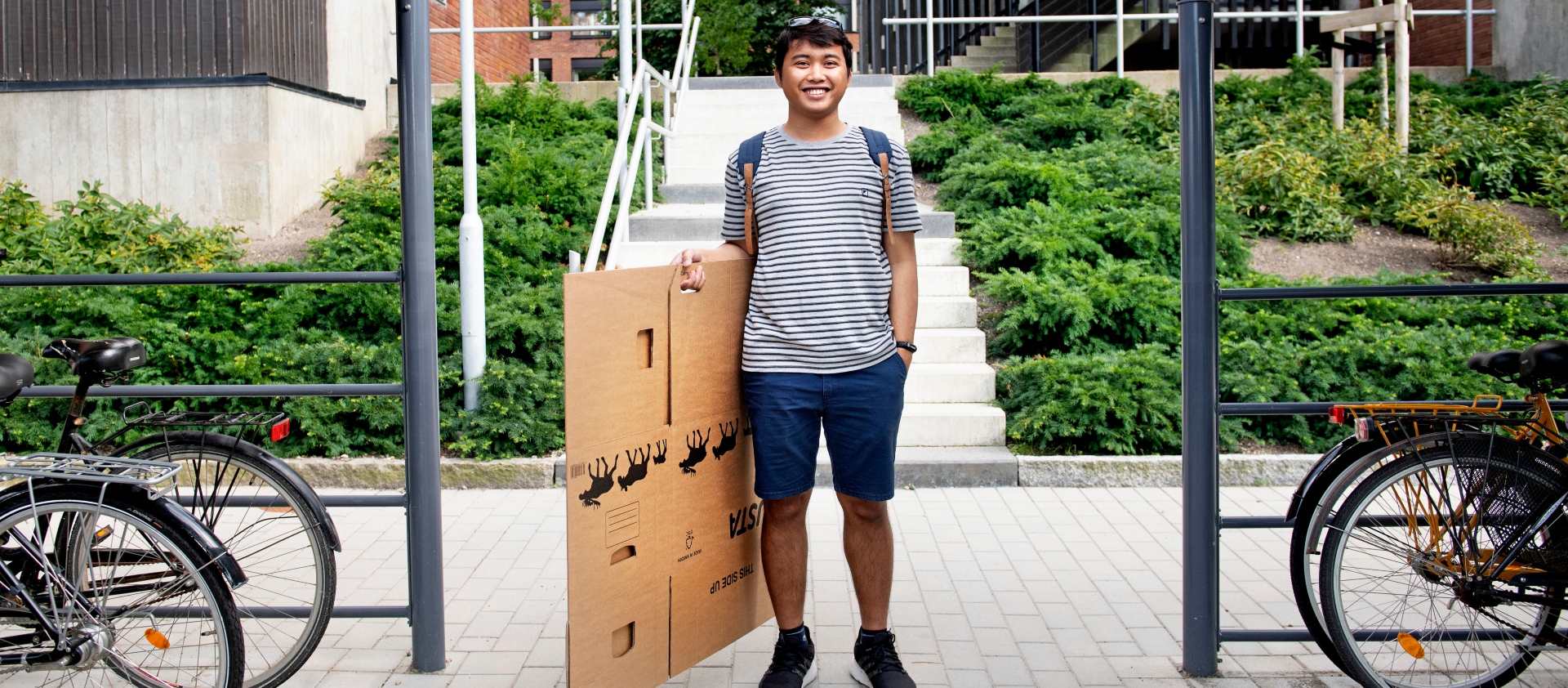 A male student with a folded moving box