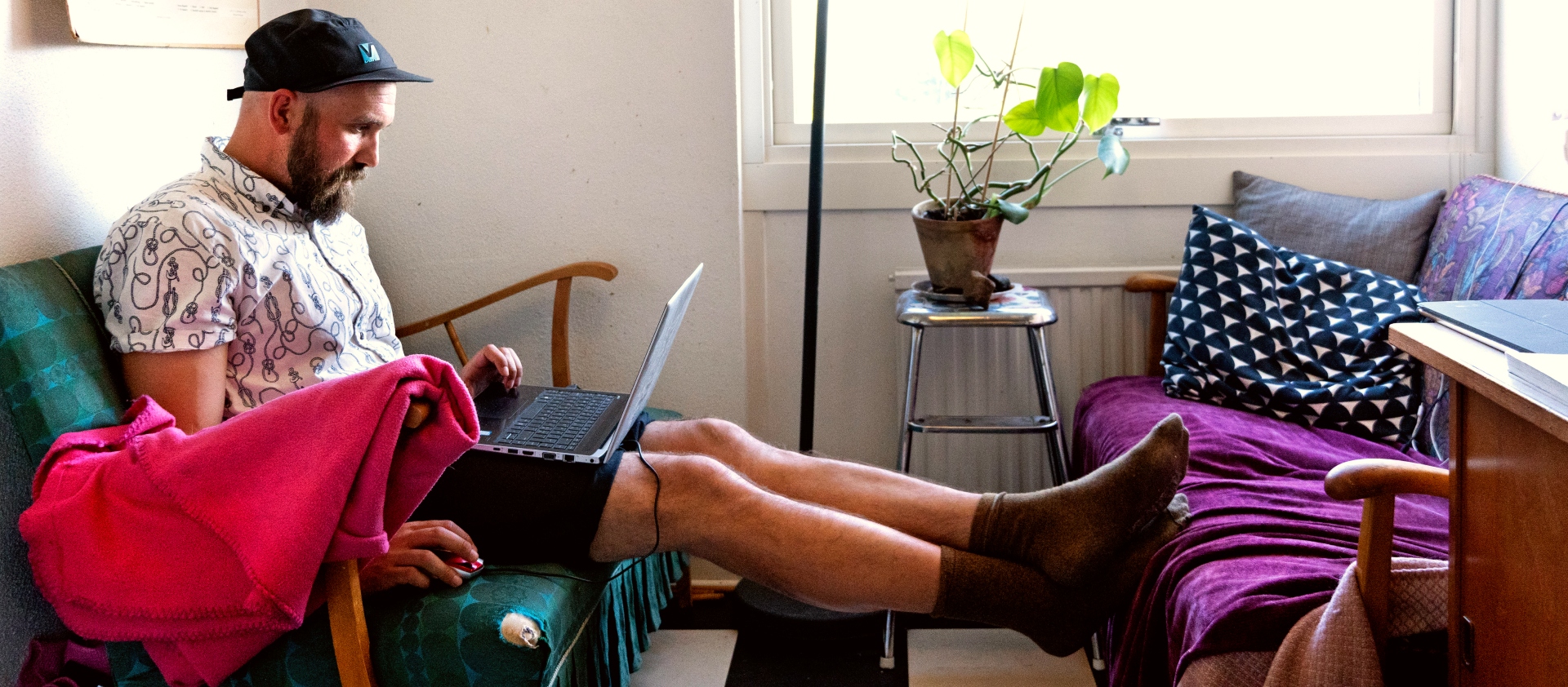 En man sitter i soffan med en dator i knäet